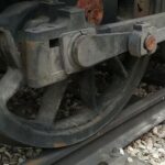 Las ruedas tractoras de una vieja locomotora de vapor descansan sobre un raíl.