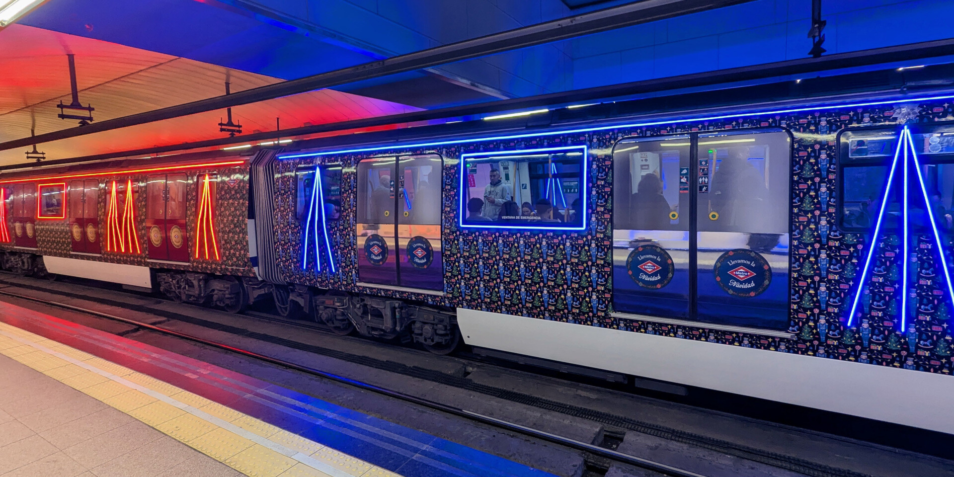 Un tren de la serie 3000 en la línea 3 de Metro de Madrid, vinilado con un patrón de motivos navideños y con cintas led de colores azul y rojo formando vértices sobre algunas ventanas y enmarcando otras.