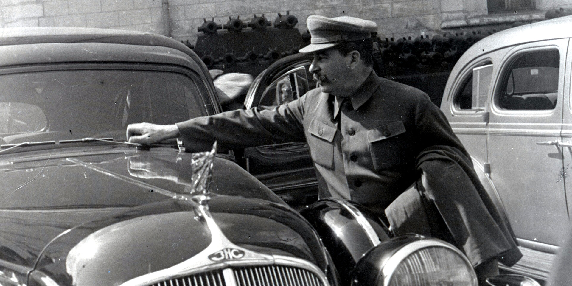 Stalin, en su uniforme de trapillo sin galones (todavía no se estilaban los looks de pechera cuajada de medallas y gorra de plato tamaño ovni) parece comprobar la dureza del capó de una limusina ZiS-101 dándole golpecitos con el puño.